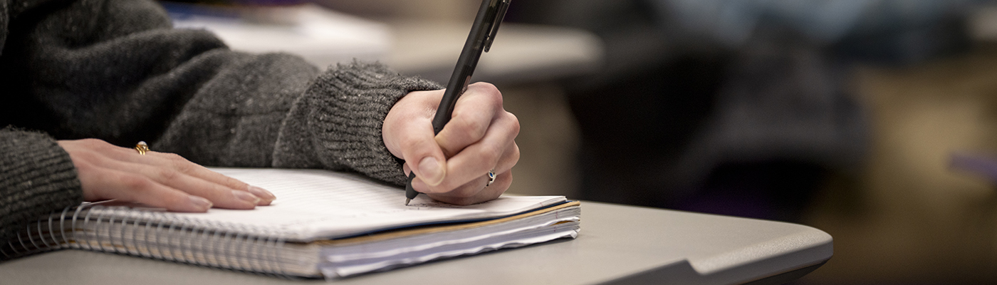  A hand holding a pencil writing in a notebook