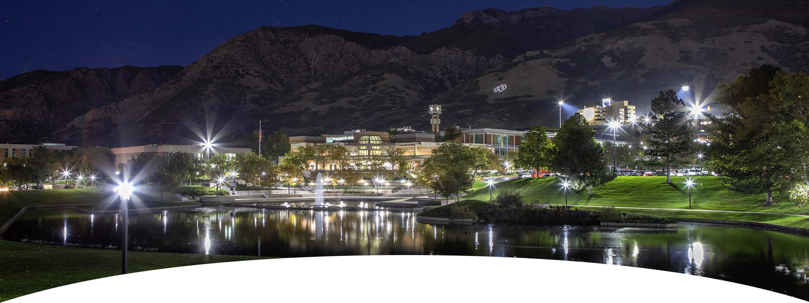 Weber State University campus at night with W lit up on hill.