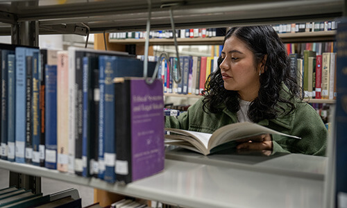 WSU student searching for books in library.