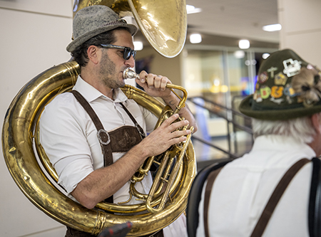 A man plays a tuba in a German outfit.