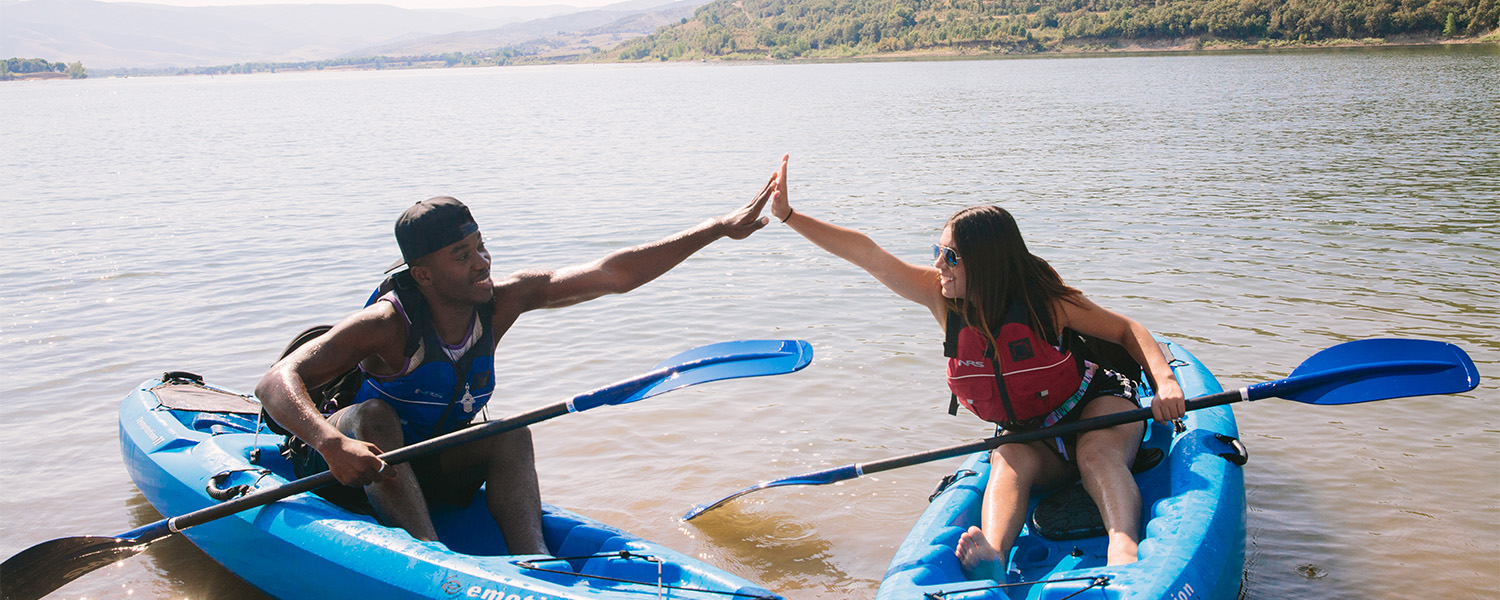 Two people high five in kayaks